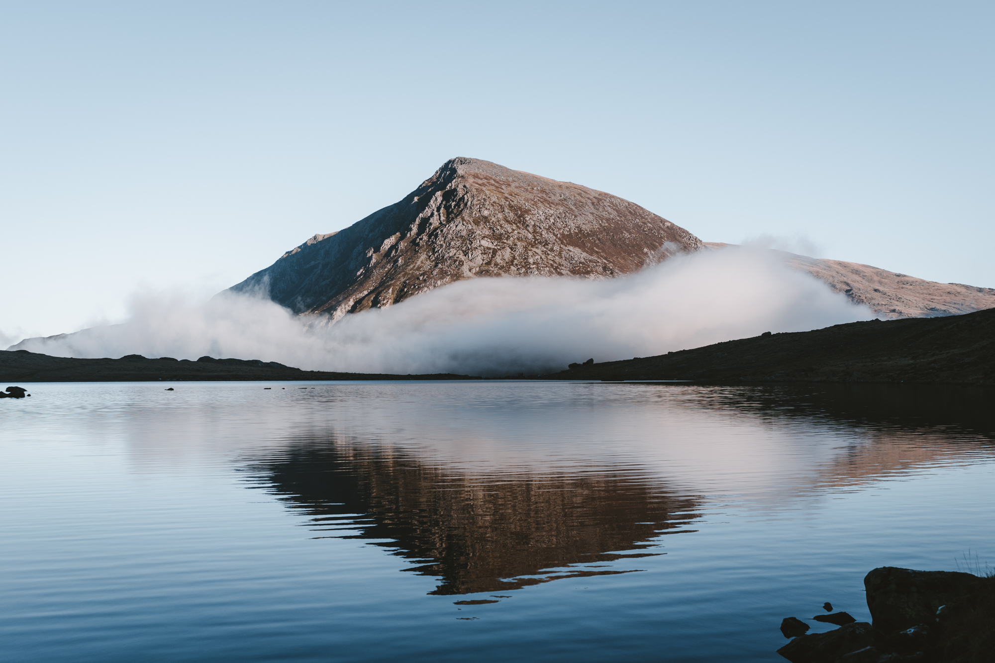 Image of a mountain with low cloud and a lake in the foreground